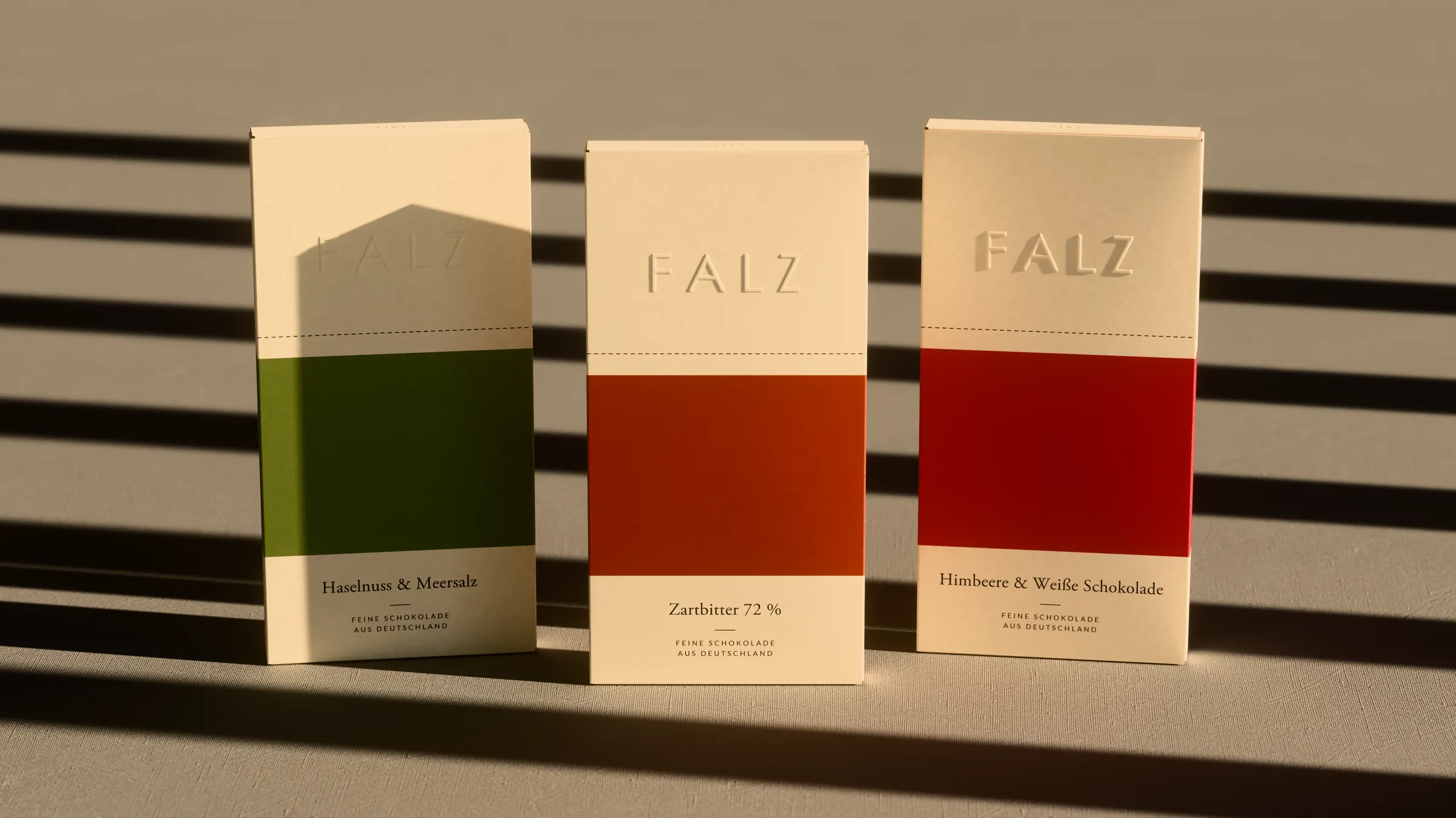 Three FALZ chocolate cartons standing in hard light through a blind