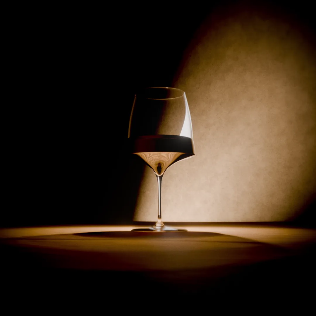 Red wine glass in a spotlight against a wall